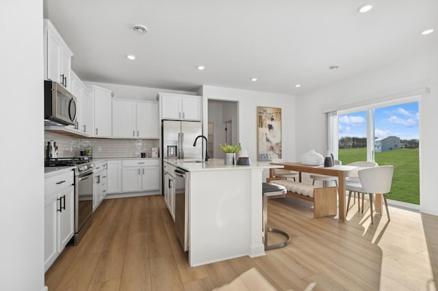 3908 Helmo Ave N, Oakdale, MN 55128 - kitchen with stainless steel appliances, light wood-type flooring, a sink, light countertops, and backsplash