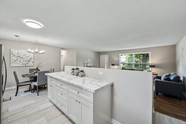 17900 Weaver Lake Dr, Maple Grove, MN 55311 - kitchen featuring a chandelier, a textured ceiling, light countertops, white cabinets, and open floor plan