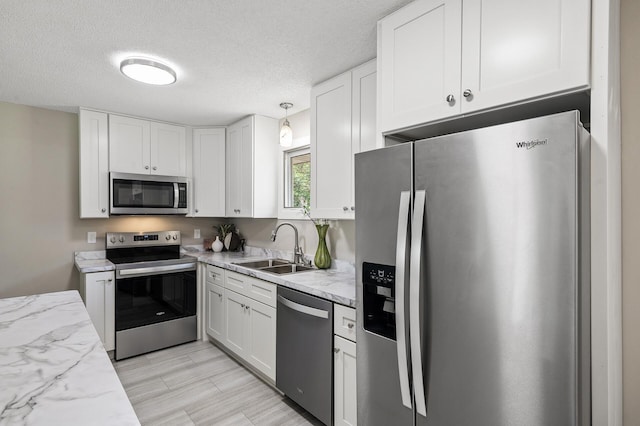 17900 Weaver Lake Dr, Maple Grove, MN 55311 - kitchen featuring appliances with stainless steel finishes, a sink, white cabinetry, a textured ceiling, and light stone countertops