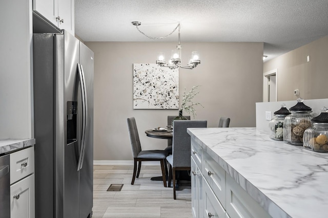 17900 Weaver Lake Dr, Maple Grove, MN 55311 - kitchen with stainless steel appliances, a chandelier, light stone counters, a textured ceiling, and white cabinetry