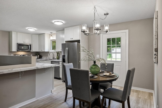17900 Weaver Lake Dr, Maple Grove, MN 55311 - dining area featuring a textured ceiling, a chandelier, baseboards, and light wood finished floors
