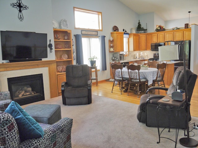 17098 Pheasant Meadow Ln SW, Prior Lake, MN 55372 - living area featuring high vaulted ceiling, light carpet, light wood-type flooring, and a glass covered fireplace