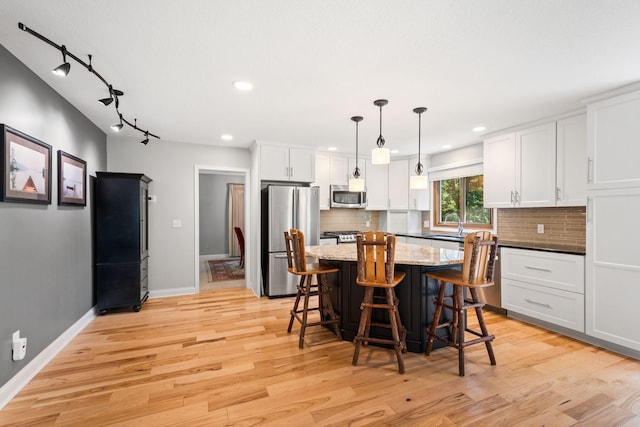 3440 Glenarden Rd, Arden Hills, MN 55112 - kitchen featuring appliances with stainless steel finishes, a breakfast bar area, white cabinetry, light wood finished floors, and decorative backsplash