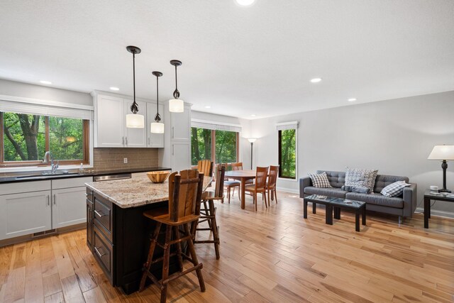 3440 Glenarden Rd, Arden Hills, MN 55112 - kitchen featuring a breakfast bar, tasteful backsplash, light wood-style flooring, pendant lighting, and open floor plan