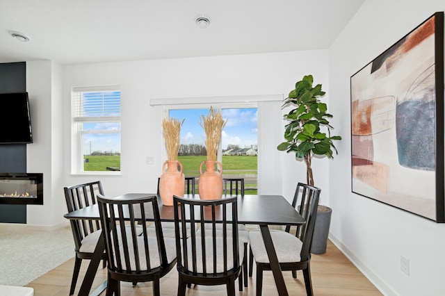 2134 Tyrone Dr, Shakopee, MN 55379 - dining room featuring a glass covered fireplace, light wood finished floors, and baseboards