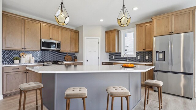 5574 130th Way N, Hugo, MN 55038 - kitchen with appliances with stainless steel finishes, decorative backsplash, a breakfast bar area, a center island, and light wood-type flooring