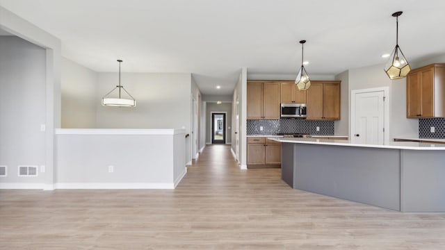 5574 130th Way N, Hugo, MN 55038 - kitchen featuring stainless steel microwave, light countertops, backsplash, brown cabinets, and recessed lighting