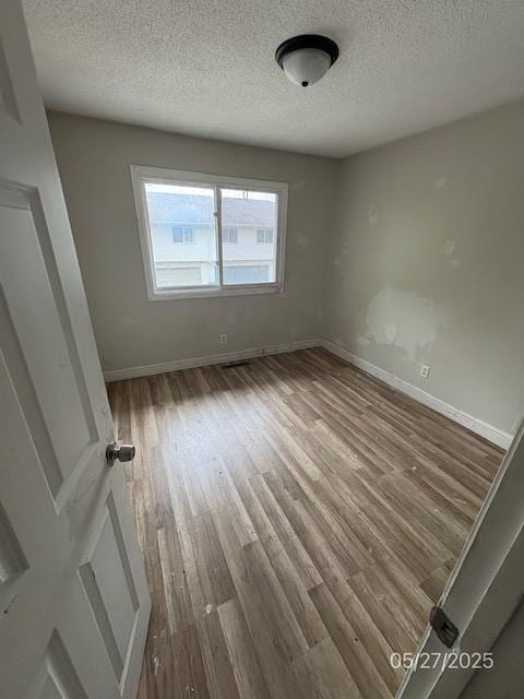 6769 Humboldt Ave N, Brooklyn Center, MN 55430 - spare room featuring wood finished floors, a textured ceiling, and baseboards