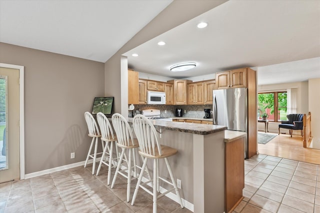 8165 240th St W, Eureka Twp, MN 55044 - kitchen featuring white microwave, range, freestanding refrigerator, a peninsula, and tasteful backsplash