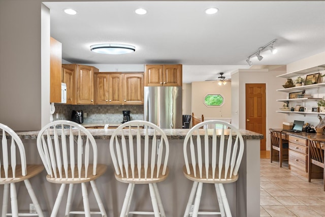 8165 240th St W, Eureka Twp, MN 55044 - kitchen with freestanding refrigerator, decorative backsplash, light tile patterned floors, a breakfast bar, and track lighting