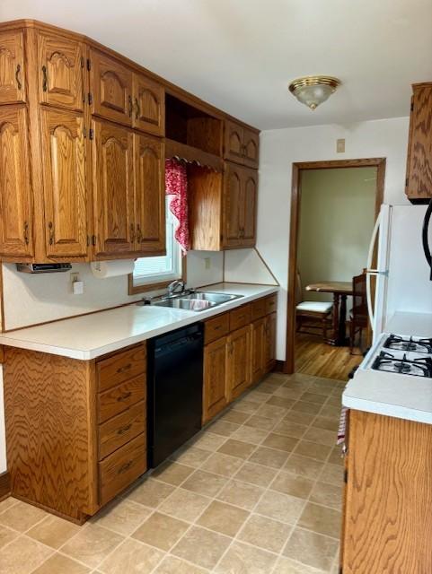455 113th Ave NW, Coon Rapids, MN 55448 - kitchen featuring black dishwasher, a sink, freestanding refrigerator, light countertops, and brown cabinetry