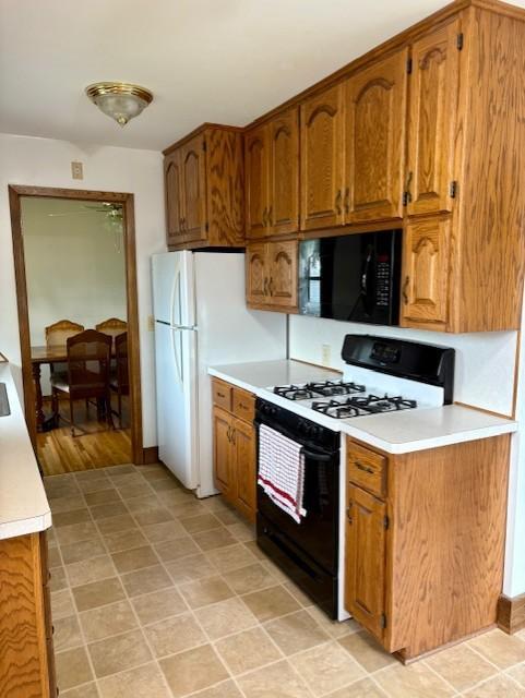 455 113th Ave NW, Coon Rapids, MN 55448 - kitchen with black microwave, gas range, brown cabinetry, light countertops, and freestanding refrigerator