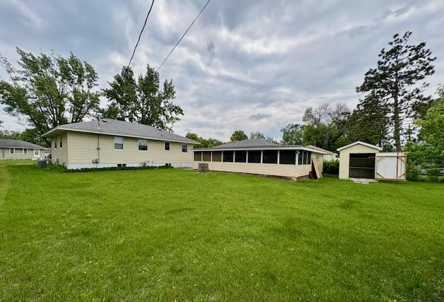 455 113th Ave NW, Coon Rapids, MN 55448 - back of house with a sunroom, an outbuilding, a yard, and central air condition unit