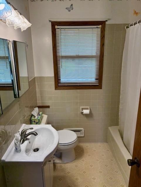 455 113th Ave NW, Coon Rapids, MN 55448 - bathroom featuring tile walls, toilet, vanity, shower / bathtub combination with curtain, and wainscoting