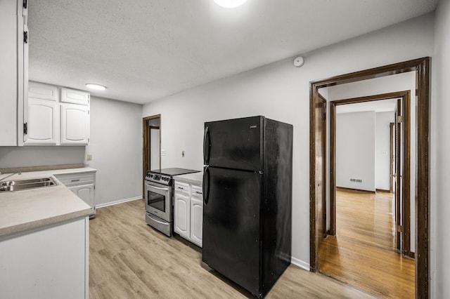 8235 Nicollet Ave S, Bloomington, MN 55420 - kitchen with freestanding refrigerator, stainless steel electric stove, a sink, white cabinets, and light wood finished floors