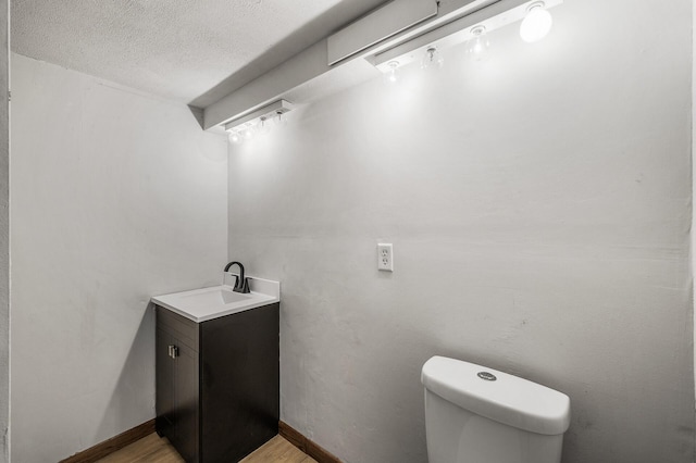 8235 Nicollet Ave S, Bloomington, MN 55420 - half bathroom with toilet, vanity, a textured ceiling, wood finished floors, and baseboards
