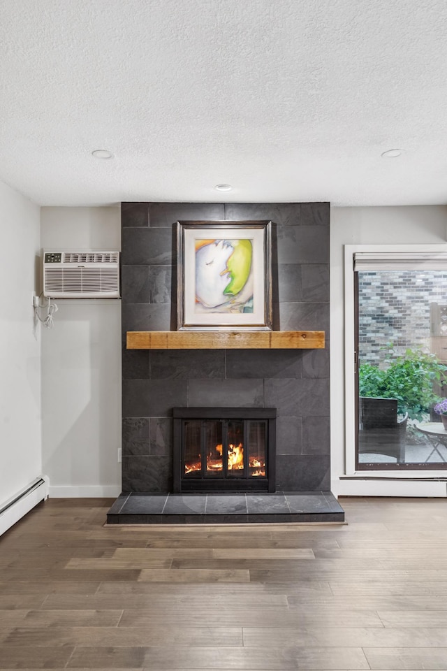 4584 Cedar Lake Rd S Unit 1, Saint Louis Park, MN 55416 - detailed view of a tiled fireplace, a textured ceiling, a wall mounted air conditioner, wood finished floors, and baseboard heating