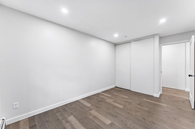 4584 Cedar Lake Rd S Unit 1, Saint Louis Park, MN 55416 - unfurnished bedroom featuring wood finished floors, a baseboard radiator, recessed lighting, and a closet