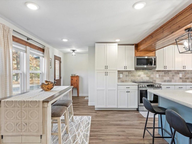 5335 Pine Beach Rd, Brainerd, MN 56401 - kitchen with appliances with stainless steel finishes, decorative backsplash, light wood-style flooring, white cabinetry, and recessed lighting