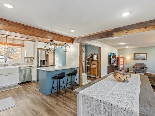 5335 Pine Beach Rd, Brainerd, MN 56401 - kitchen with appliances with stainless steel finishes, white cabinets, light wood finished floors, a kitchen breakfast bar, and recessed lighting