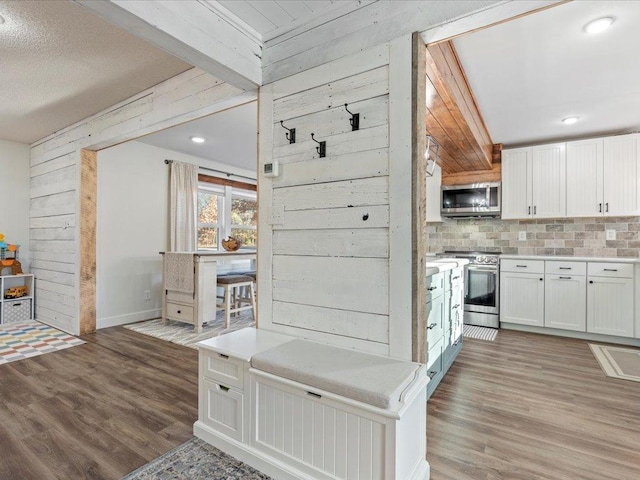 5335 Pine Beach Rd, Brainerd, MN 56401 - kitchen featuring stainless steel appliances, wooden walls, light wood finished floors, backsplash, and white cabinets