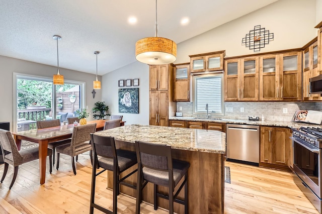 5691 Birch Trl, Shoreview, MN 55126 - kitchen with stainless steel appliances, lofted ceiling, a sink, brown cabinetry, and light wood-type flooring