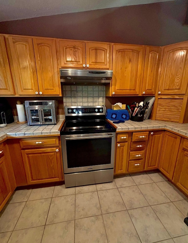 4488 Konieska Rd, Moose Lake, MN 55767 - kitchen featuring stainless steel range with electric cooktop, under cabinet range hood, tile countertops, and light tile patterned flooring
