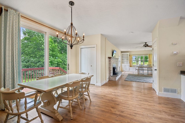2256 40th Ave Unit X, East Farmington, WI 54020 - dining space featuring light wood-type flooring, baseboards, ceiling fan, a fireplace with raised hearth, and a chandelier