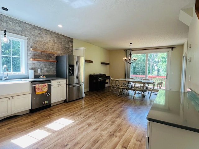 2256 40th Ave, East Farmington, WI 54020 - kitchen with stainless steel appliances, white cabinetry, light wood-type flooring, a chandelier, and decorative light fixtures