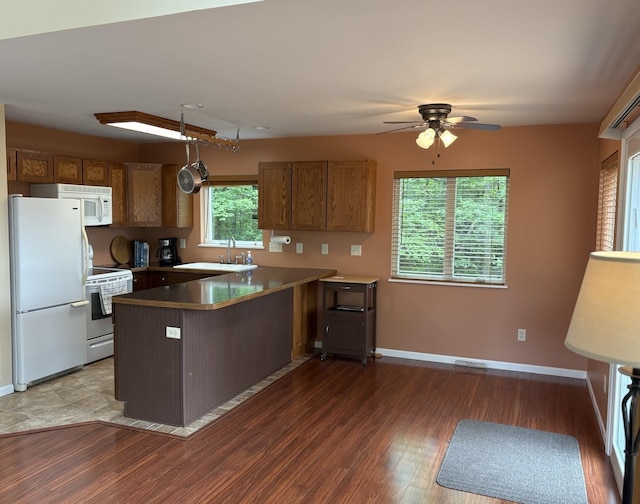 32813 Whispering Springs Loop, Erhard, MN 56534 - kitchen with white appliances, a peninsula, ceiling fan, brown cabinetry, and wood finished floors