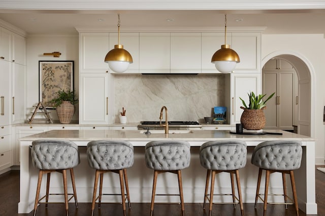 55XX Mcguire Rd, Edina, MN 55439 - kitchen with backsplash, white cabinetry, an island with sink, light countertops, and pendant lighting