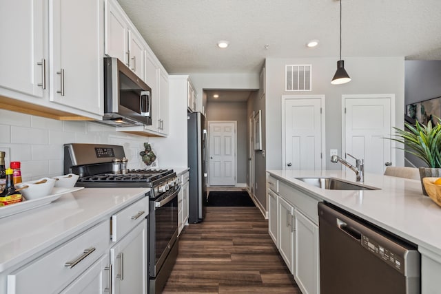 19981 62nd Pl, Corcoran, MN 55340 - kitchen featuring stainless steel appliances, white cabinets, light countertops, dark wood-type flooring, and tasteful backsplash