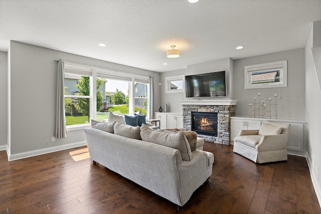 15827 Ethan Trl N, Hugo, MN 55038 - living area featuring a stone fireplace, baseboards, dark wood finished floors, recessed lighting, and a textured ceiling