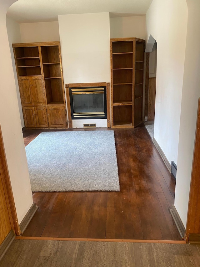 8 Dayton Ave SE, Wadena, MN 56482 - unfurnished living room with arched walkways, dark wood-style floors, and a glass covered fireplace