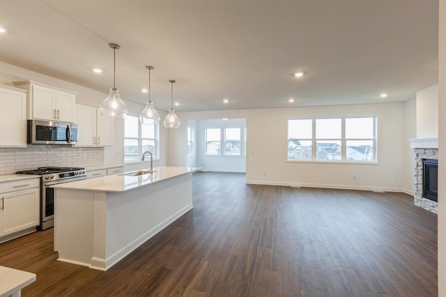 20119 68th Pl, Corcoran, MN 55340 - kitchen with appliances with stainless steel finishes, open floor plan, a center island with sink, light countertops, and white cabinets
