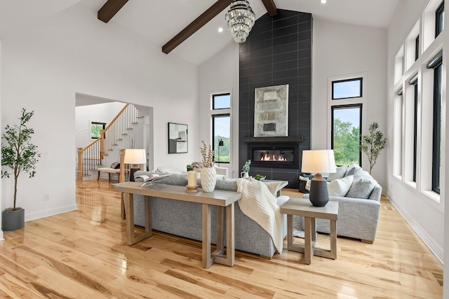 9743 Frontier Ln, Lakeville, MN 55044 - living area featuring high vaulted ceiling, beam ceiling, light wood finished floors, stairs, and a tiled fireplace