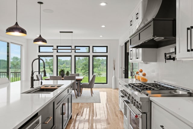 9743 Frontier Ln, Lakeville, MN 55044 - kitchen with double oven range, premium range hood, light countertops, light wood-type flooring, and hanging light fixtures