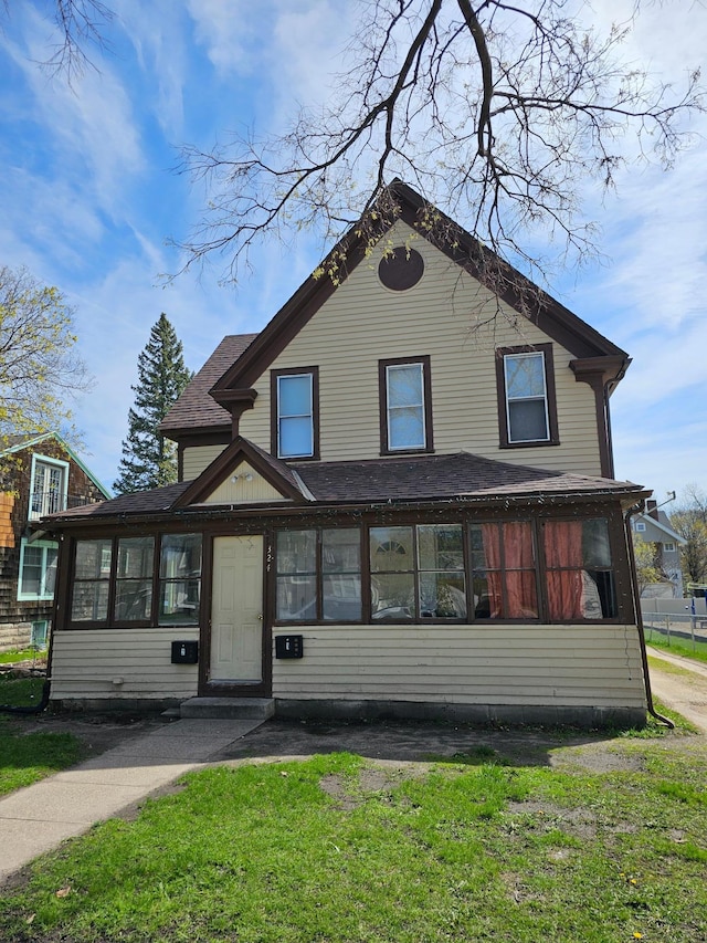 324 Holcombe Ave, Litchfield, MN 55355 - view of front of property with a sunroom, a front yard, and a shingled roof
