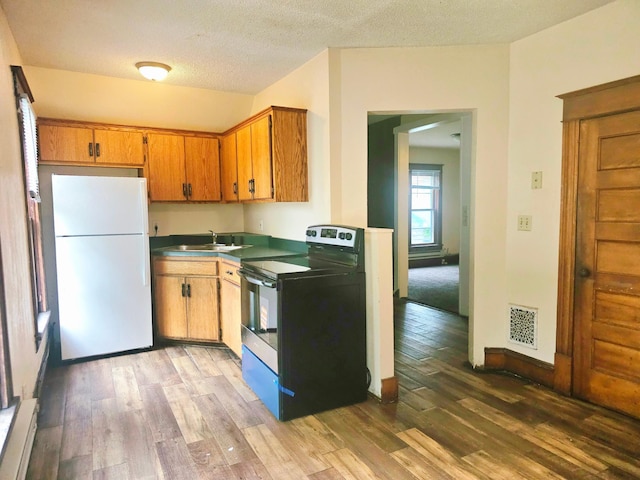 324 Holcombe Ave, Litchfield, MN 55355 - kitchen with stainless steel electric stove, freestanding refrigerator, light wood-style flooring, brown cabinetry, and a baseboard heating unit