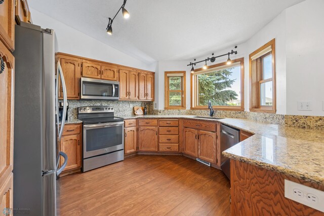 3306 26th Ave S, Fargo, ND 58103 - kitchen featuring appliances with stainless steel finishes, track lighting, wood finished floors, vaulted ceiling, and light stone counters