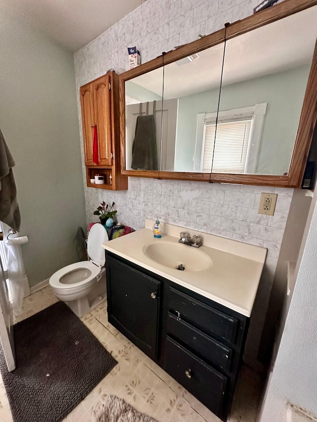 506 Marshall St, Marshall, MN 56258 - bathroom featuring toilet, vanity, backsplash, and tile walls