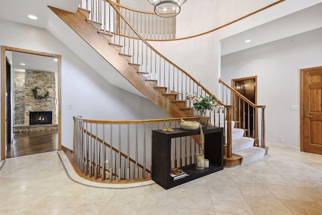 10481 Bluff Rd, Eden Prairie, MN 55347 - stairway with a towering ceiling, tile patterned floors, a stone fireplace, recessed lighting, and a chandelier