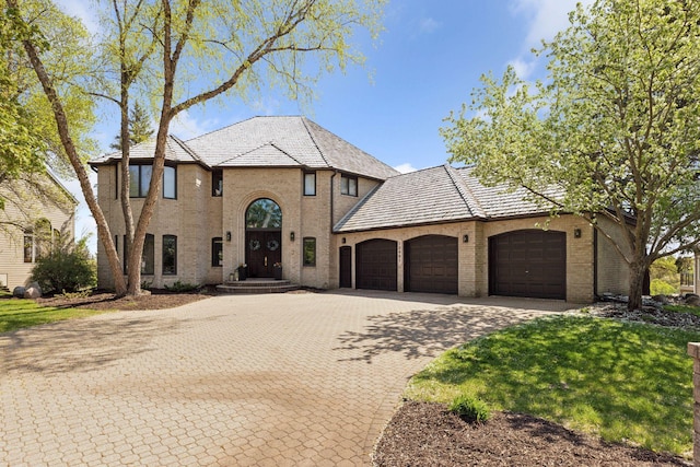 10481 Bluff Rd, Eden Prairie, MN 55347 - french country inspired facade featuring an attached garage, brick siding, a high end roof, decorative driveway, and a front yard