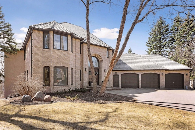 10481 Bluff Rd, Eden Prairie, MN 55347 - french country home featuring driveway, a garage, and brick siding