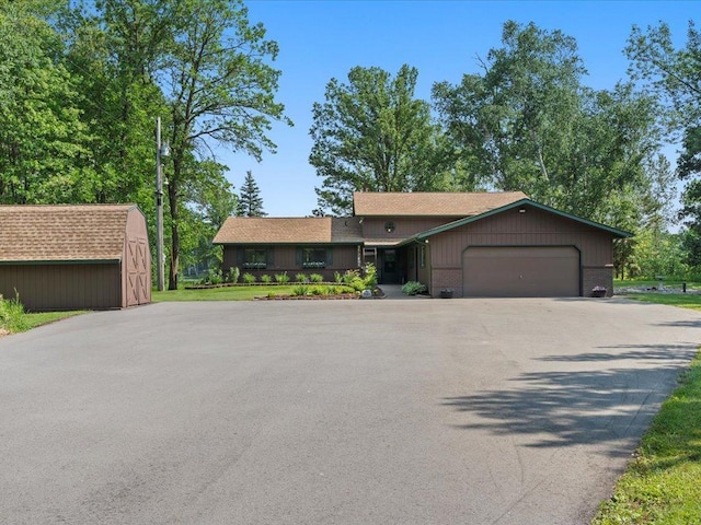 15473 Wilderness Trl, Crosslake, MN 56442 - view of front of property with asphalt driveway, an attached garage, and a storage unit