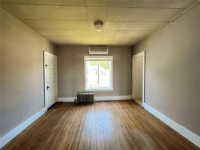 403 2nd St, Austin, MN 55912 - unfurnished room featuring radiator heating unit, dark wood finished floors, baseboards, and a wall mounted air conditioner