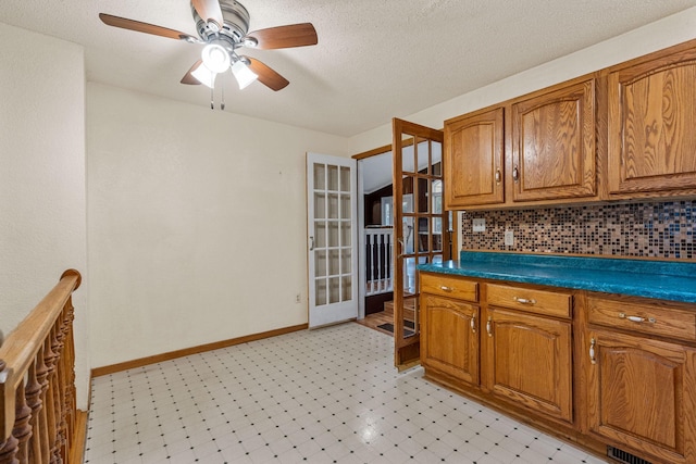2101 6th Ave NE, Austin, MN 55912 - kitchen with brown cabinetry, a ceiling fan, decorative backsplash, french doors, and dark countertops