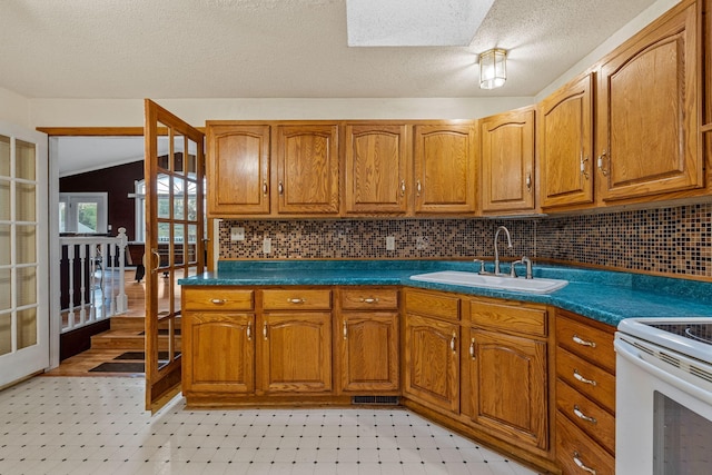 2101 6th Ave NE, Austin, MN 55912 - kitchen with a sink, light flooring, brown cabinets, tasteful backsplash, and a textured ceiling