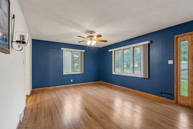 2101 6th Ave NE, Austin, MN 55912 - empty room featuring wood finished floors, healthy amount of natural light, and a textured ceiling