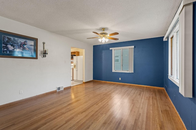 2101 6th Ave NE, Austin, MN 55912 - spare room with wood finished floors, ceiling fan, baseboards, and a textured ceiling